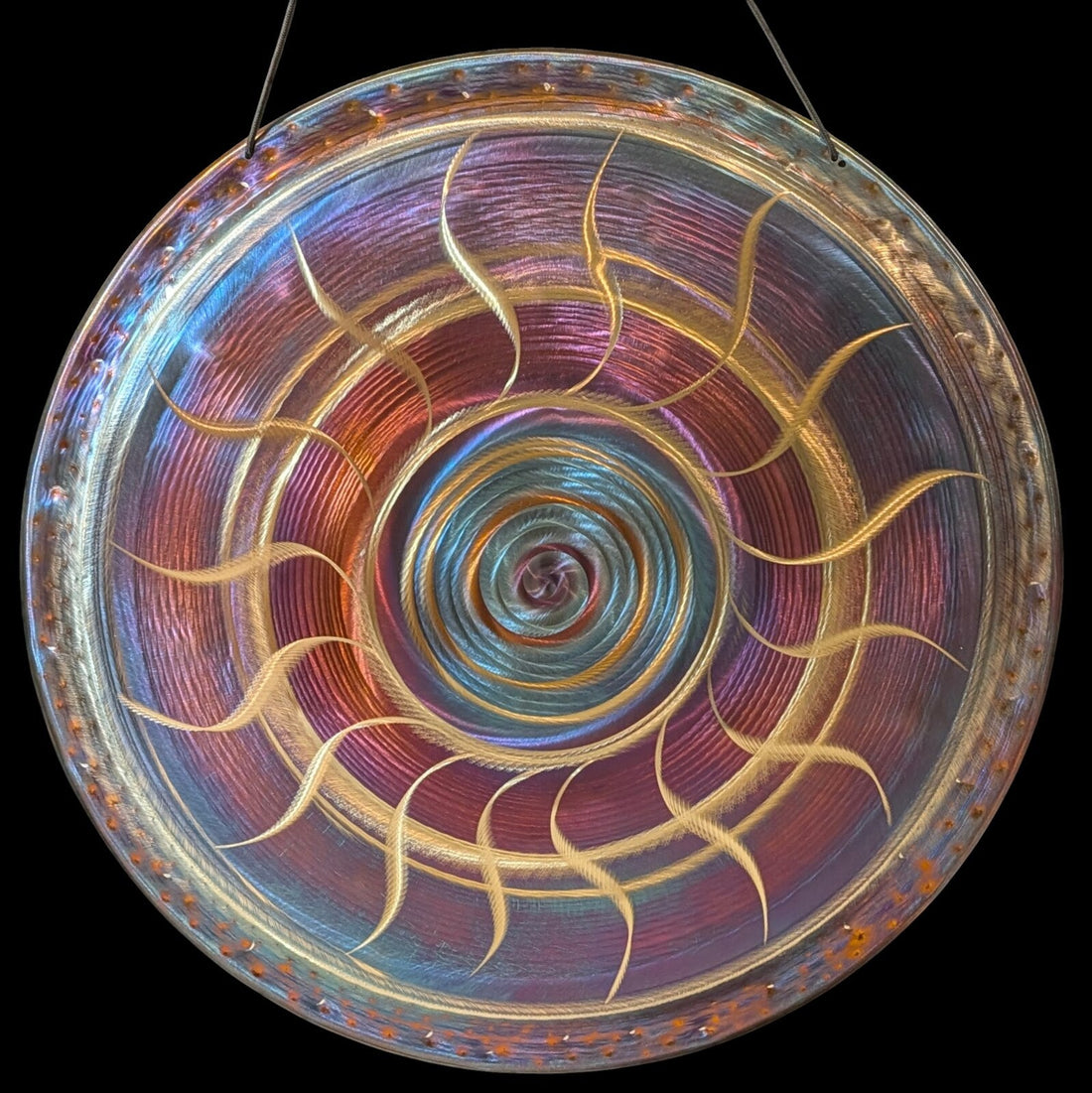 Iridescent hand-finished gong with a golden spiral pattern, hanging on a cord