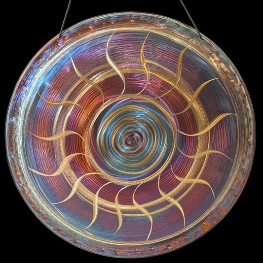 Iridescent hand-finished gong with a golden spiral pattern, hanging on a cord
